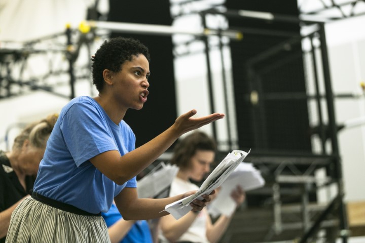 Danielle is reading from a script with one hand stretched in front of her 	                gesturing with a look of anger. Catriona and Anne are in the  background but are out of focus